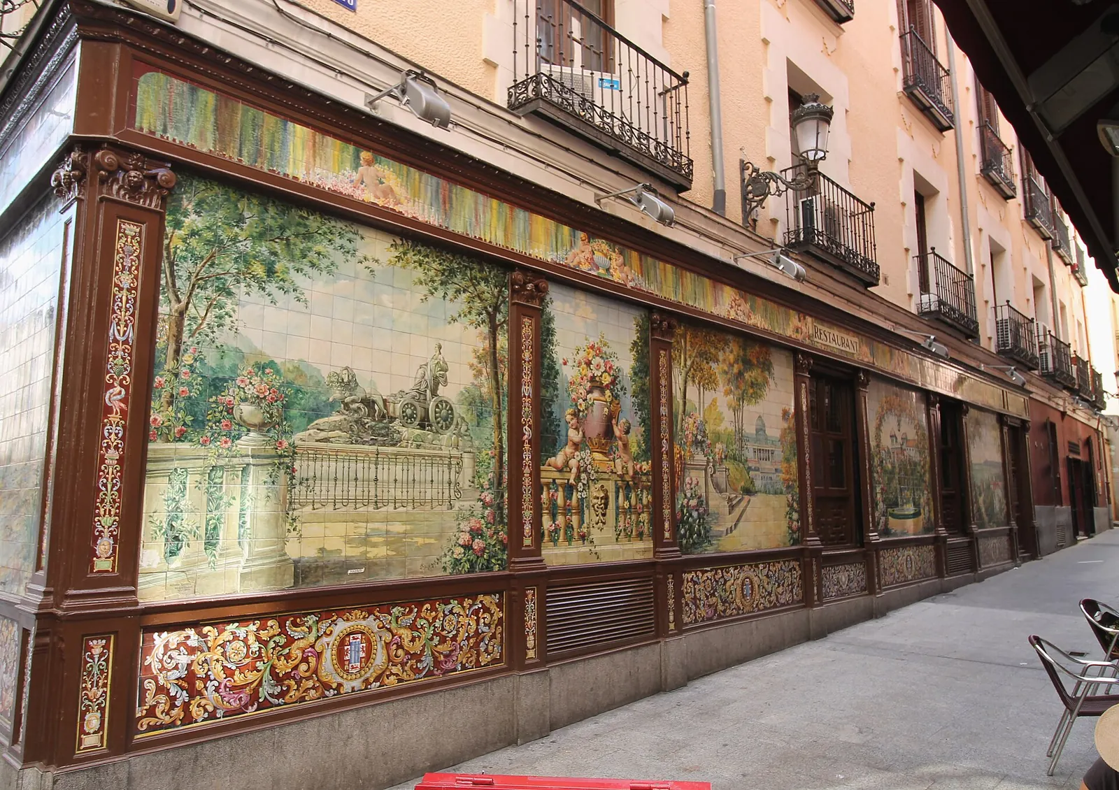 A painted ceramic panel of the Cibeles fountain with its lions, framed in dark carved wood, on the side wall of the former Villa Rosa