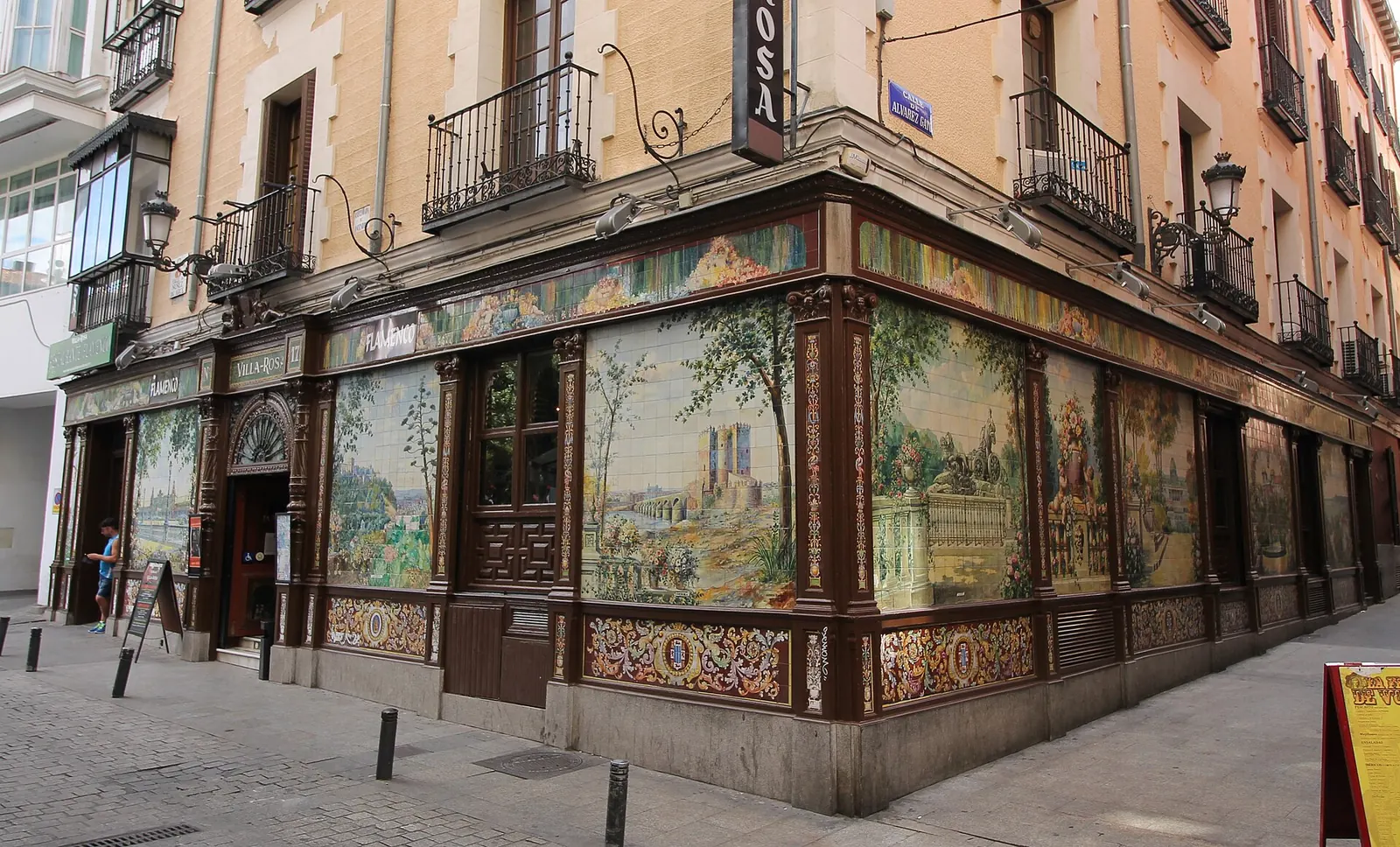 The tiled corner of the former Villa Rosa on Plaza de Santa Ana, with painted ceramic panels in dark wooden frames above a decorated tile base